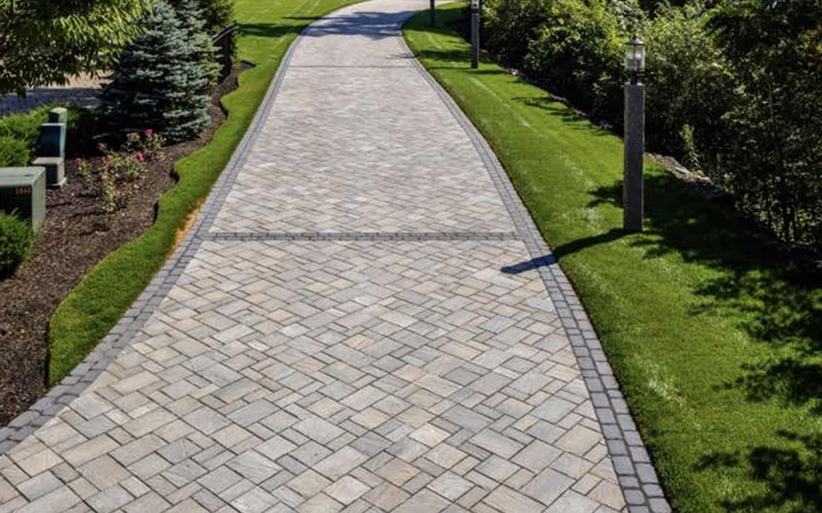 Elegant stone driveway with patterned pavers and manicured landscaping built with E expert outdoor living designs in Fort Worth, TX