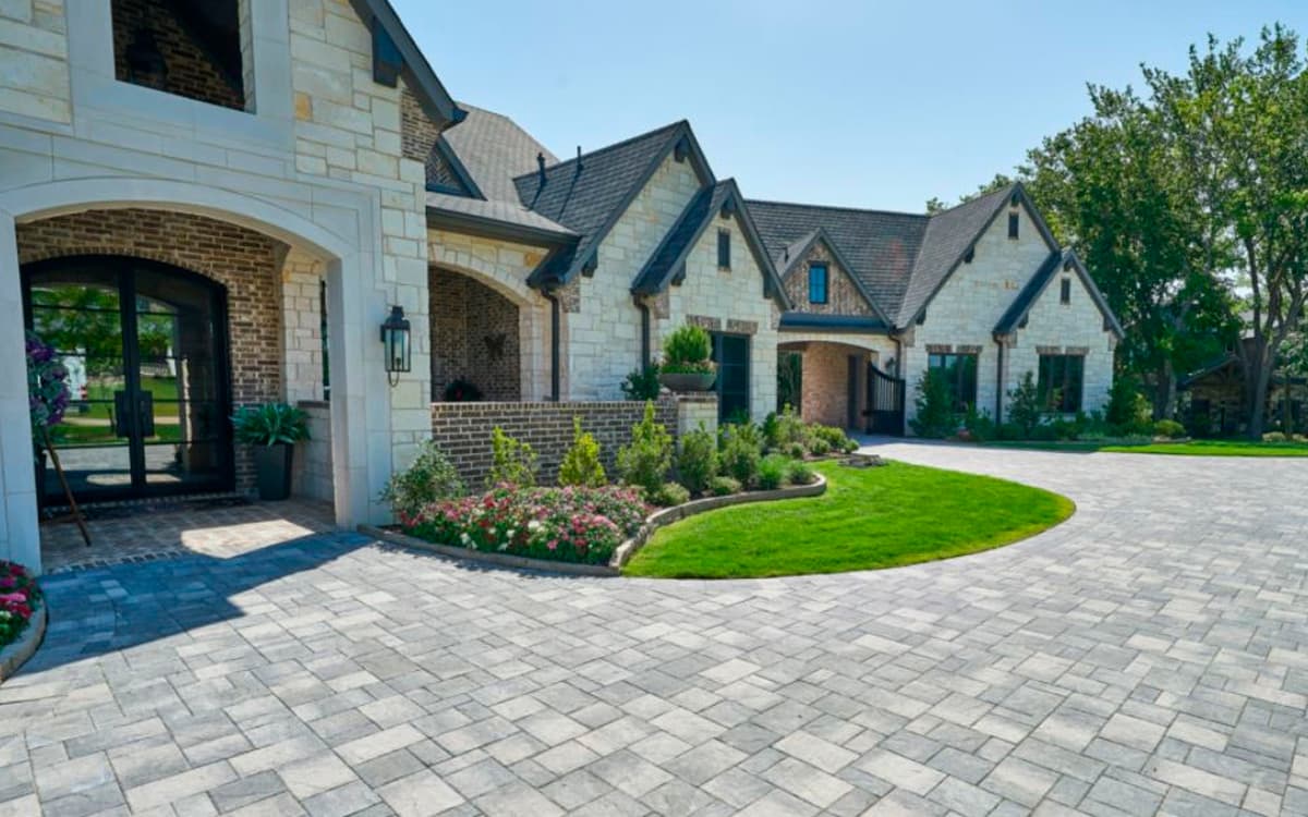 Elegant stone driveway and landscaped entrance of a luxury home built with outdoor living designs in Fort Worth, TX