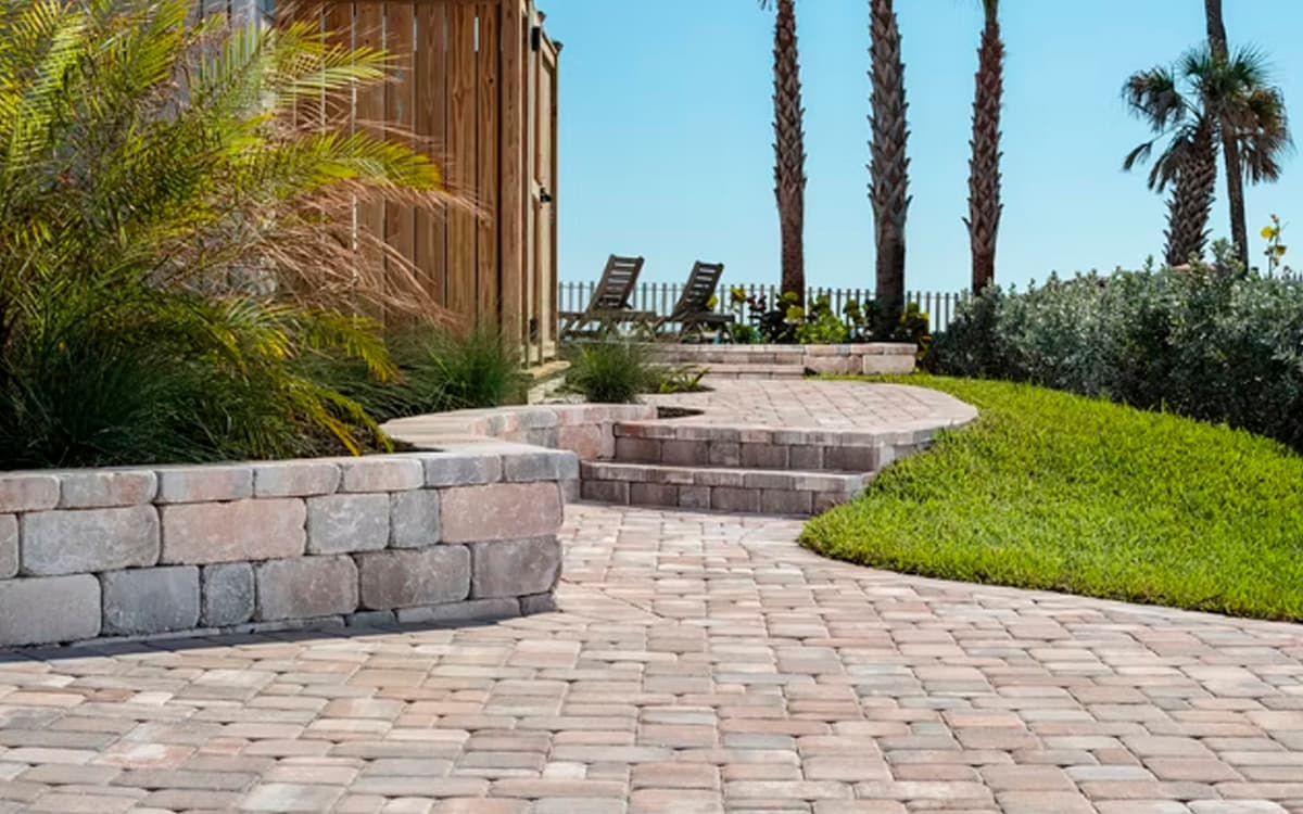 Stone walkway with paver steps and garden walls surrounded by palm trees buil with expert outdoor living designs in Fort Worth, TX