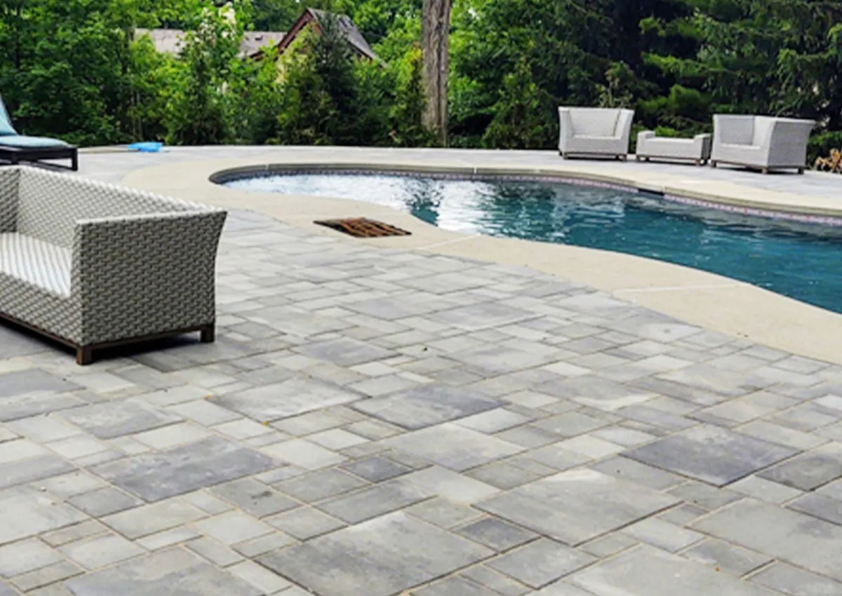 backyard pool area with stone paver deck and modern outdoor seating designed by pool deck contractors in Fort Worth, TX