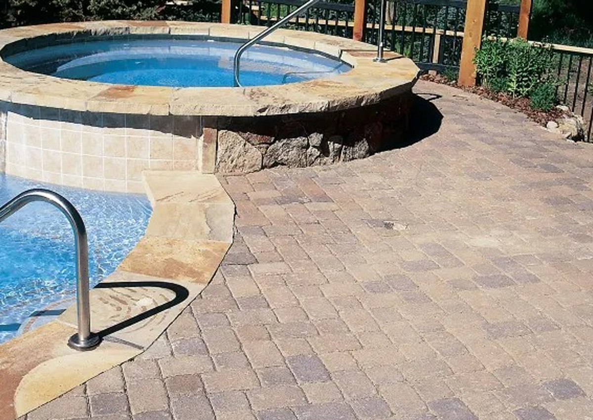 stone pool deck with raised spa and tile border installed by expert pool deck contractors in Denton County, TX