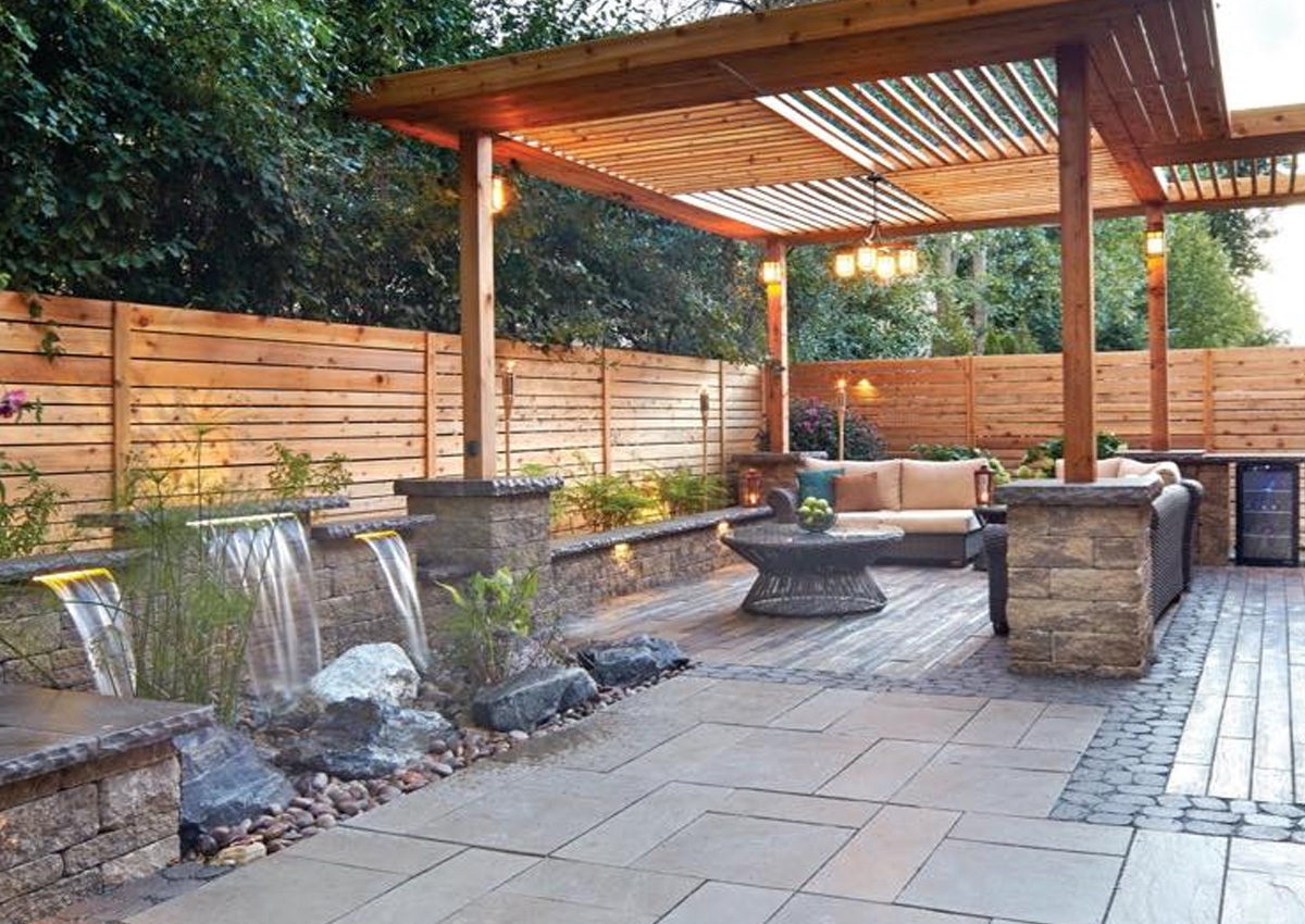 Outdoor patio with wooden pergola, water features, and stone seating area built by luxury outdoor design in Fort Worth, TX