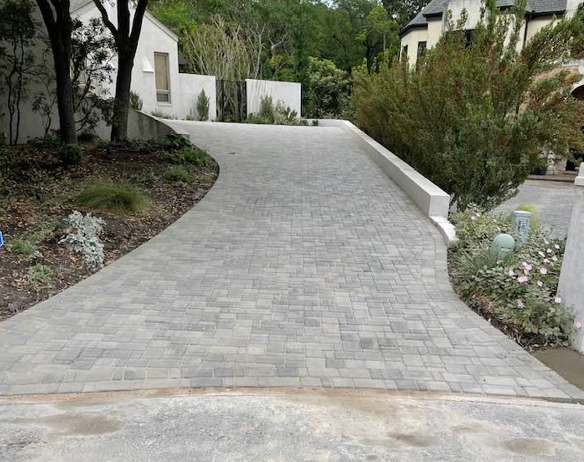 Holistic Patio Hardscaping Services in Fort Worth, TX - Holistic Patio Custom Driveway Installation in Fort Worth TX g2 curved gray stone paver driveway surrounded by landscaped garden after expert driveway installation in Fort Worth, TX