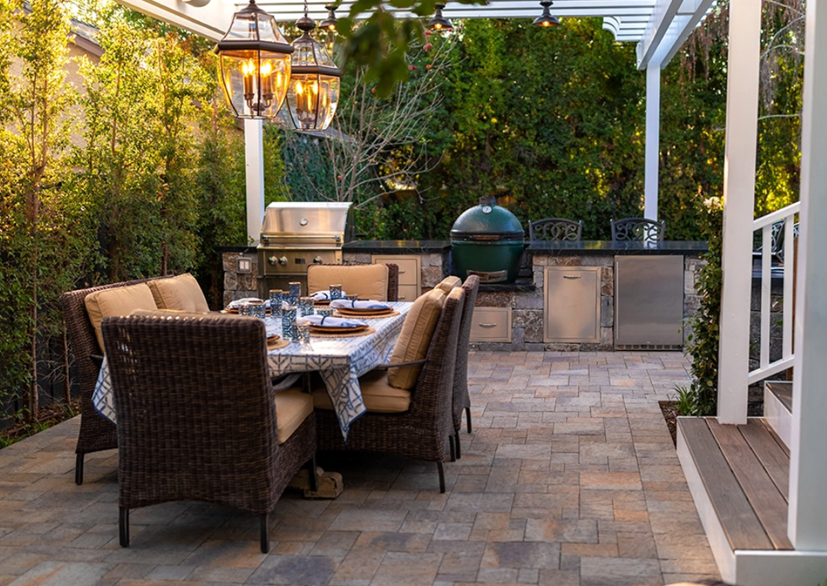 Outdoor dining area with wicker chairs, grill station, and paver flooring with outdoor living designs in Fort Worth, TX