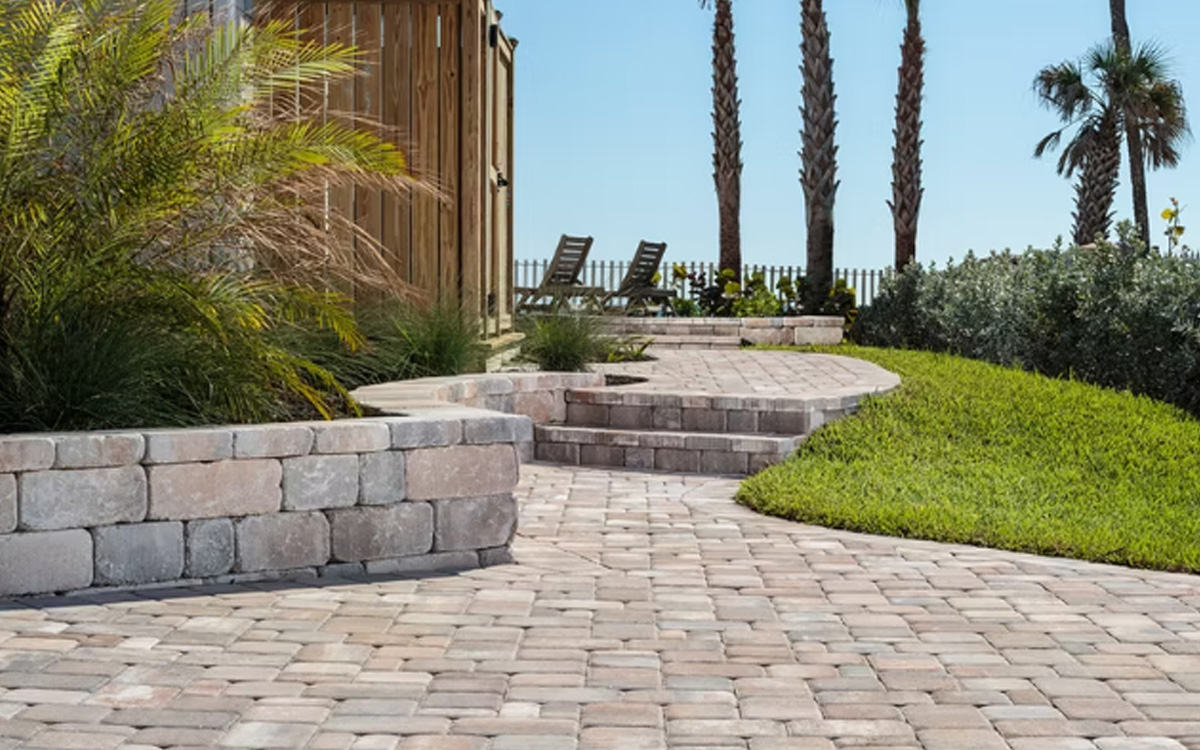 Stone walkway with paver steps and garden walls surrounded by palm trees buil with expert outdoor living designs in Fort Worth, TX