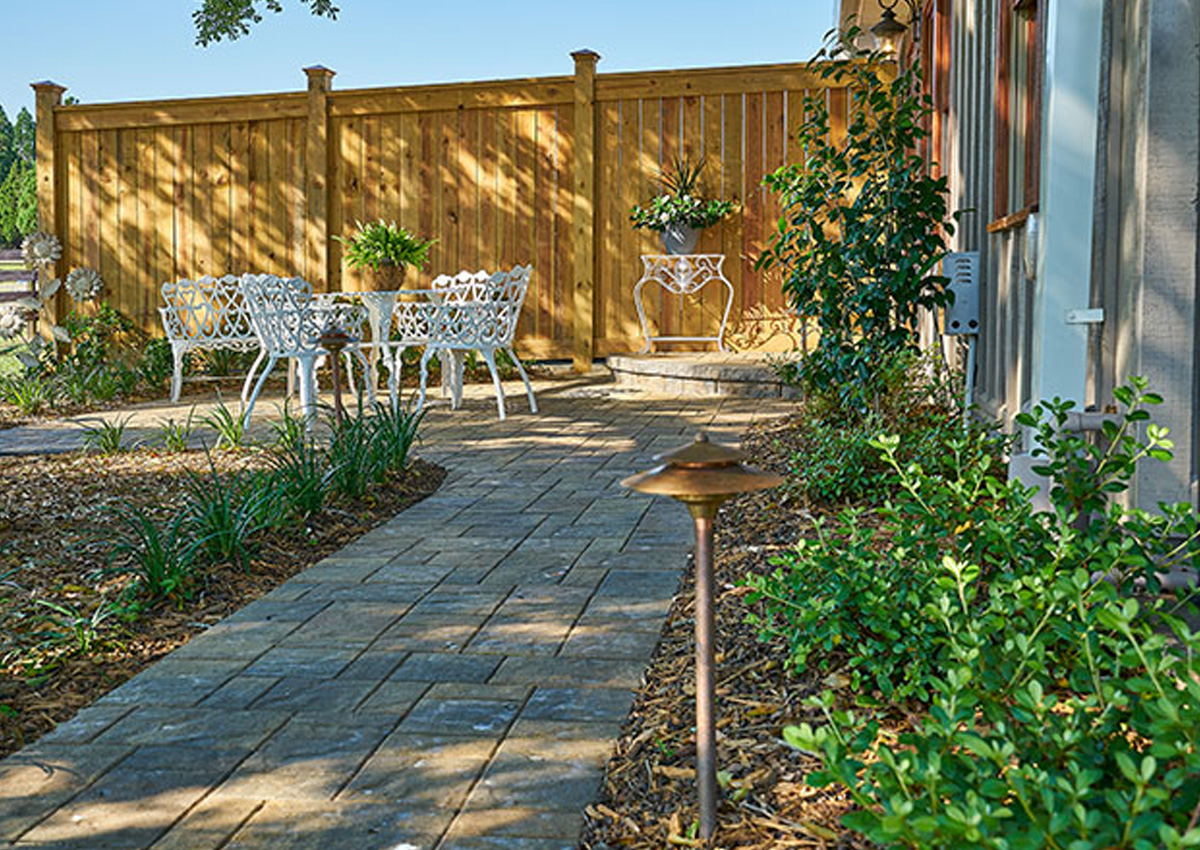 garden path with stone pavers leading to white patio furniture created through professional paver walkway installation in Fort Worth, TX