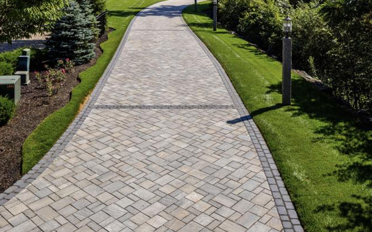 Elegant stone driveway with patterned pavers and manicured landscaping built with E expert outdoor living designs in Fort Worth, TX