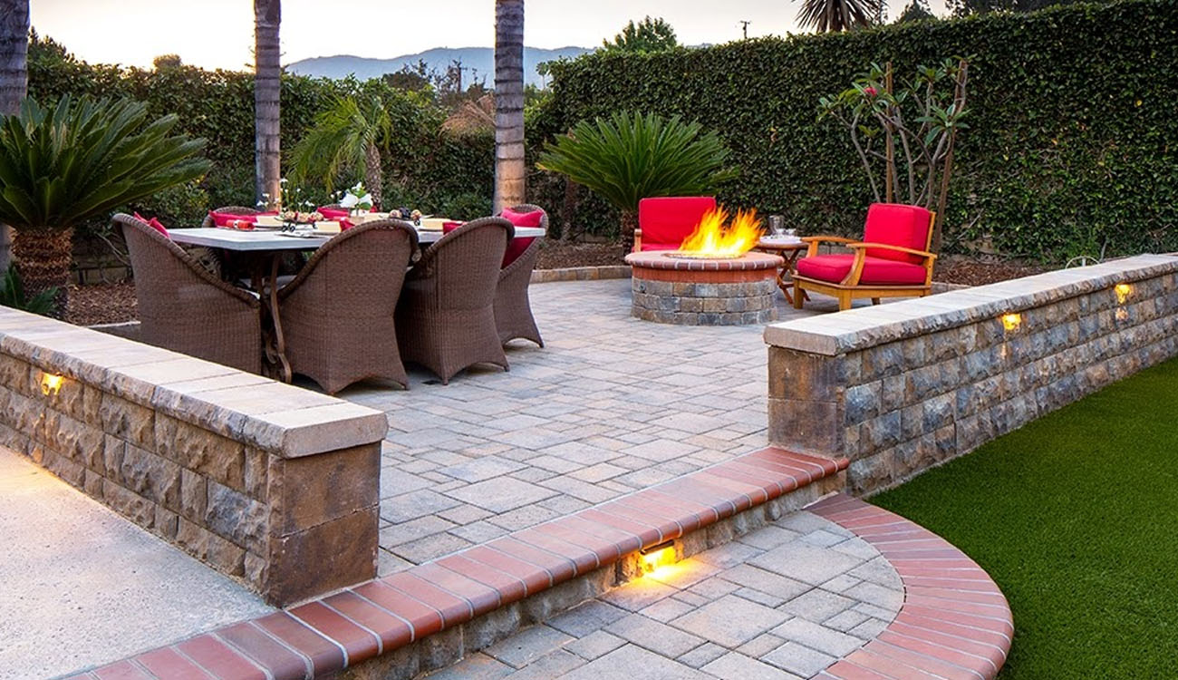 stylish outdoor patio with brick fire pit, dining area, and warm lighting, showcasing Fireplace Backyard Ideas for cozy gatherings