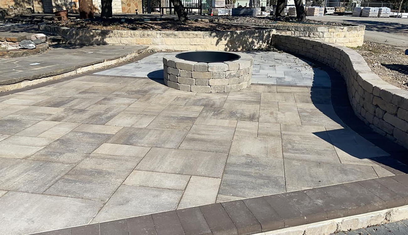 Holistic Patio Hardscaping Services in Fort Worth, TX - Outdoor Fire Pit Ideas That Warm Up Your Backyard in Denton County c1 Backyard patio with a round stone fire pit and spacious paver layout, offering outdoor fire pit ideas for inviting and functional gathering spaces