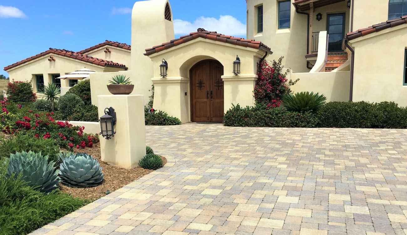 Light-toned paver driveway in Fort Worth, TX, surrounded by lush landscaping, offering stylish paver driveway ideas for any home.