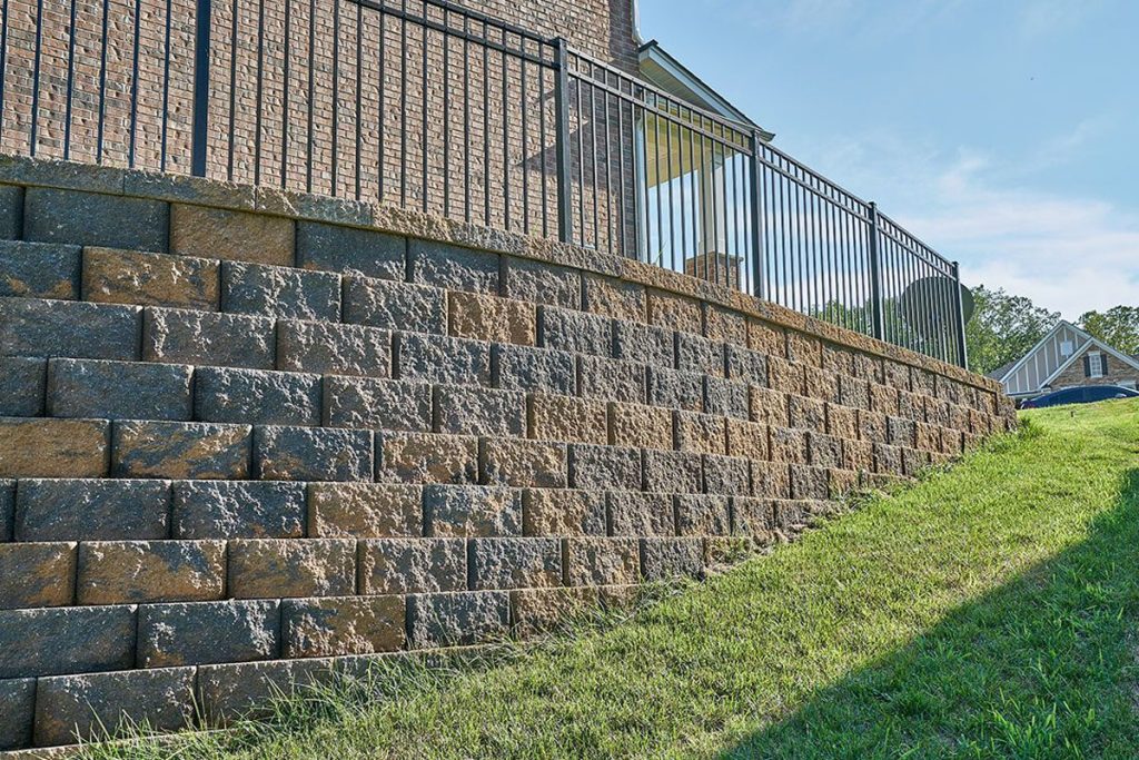 Tiered retaining wall ideas using textured stone blocks to support a sloped backyard and create a clean, modern landscape design